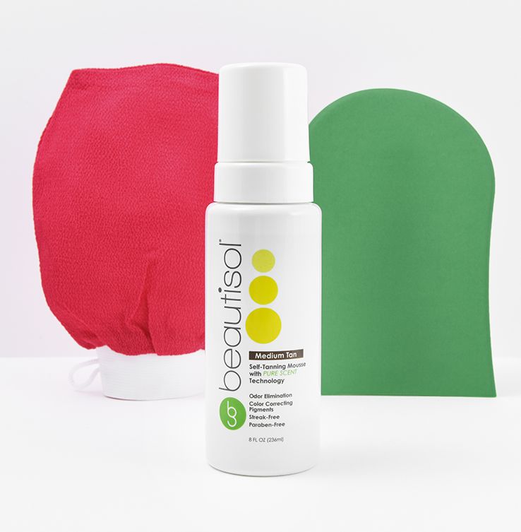 A bottle of facial cleanser next to a red mitt and green glove.