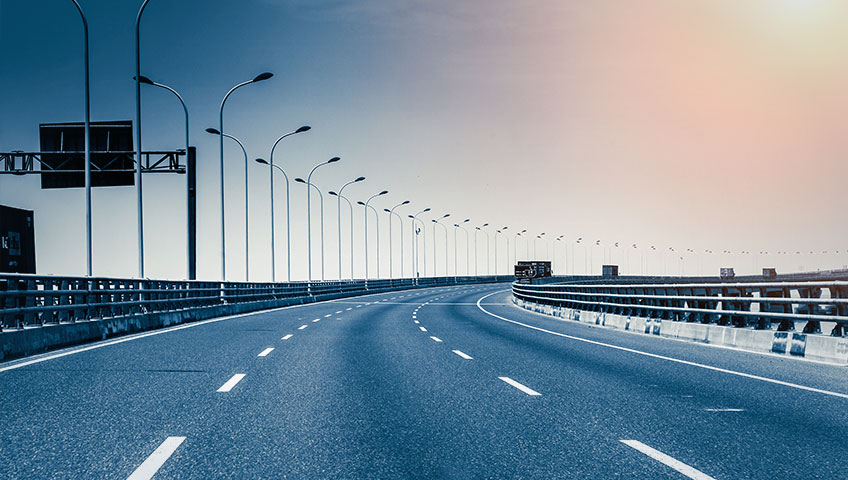 A highway with street lights and a blue sky