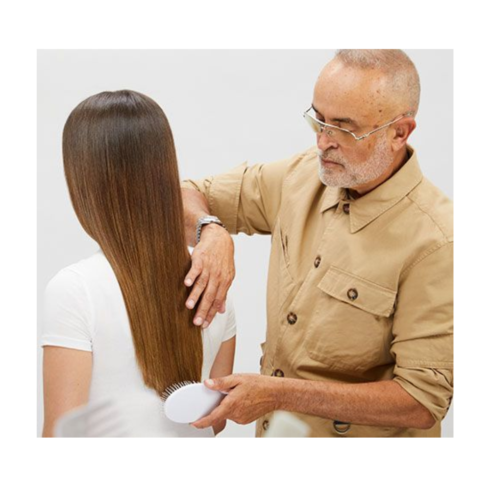 A man is shaving his long hair while the woman looks on.
