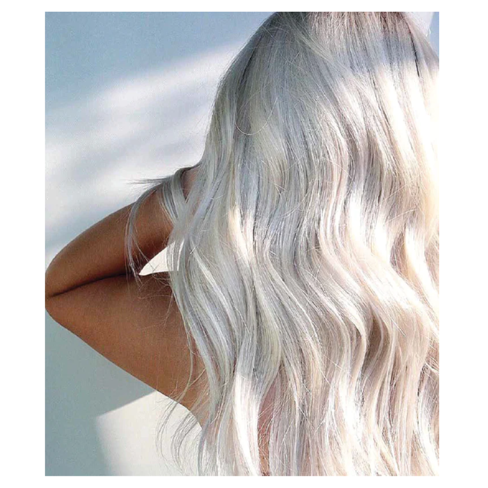 A woman with long white hair is standing in front of the wall.